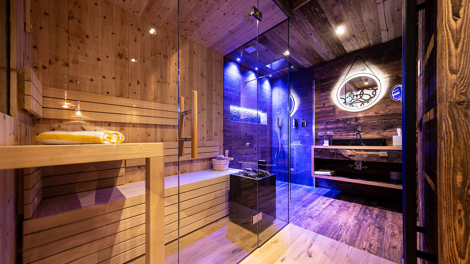 Privater Wellnessbereich des Alpine Zimmers mit finnischer Sauna, beleuchteter Erlebnisdusche und modernem Badezimmer.