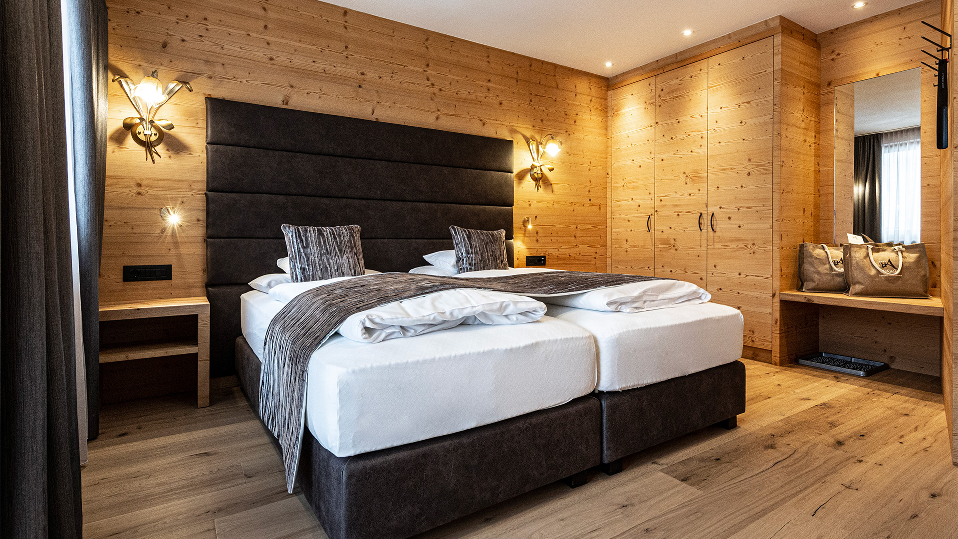 Klassikzimmer des Hotel Arkadia: warme Holzwände, zwei Doppelbetten mit weißer Bettwäsche und gedämpftes Licht.