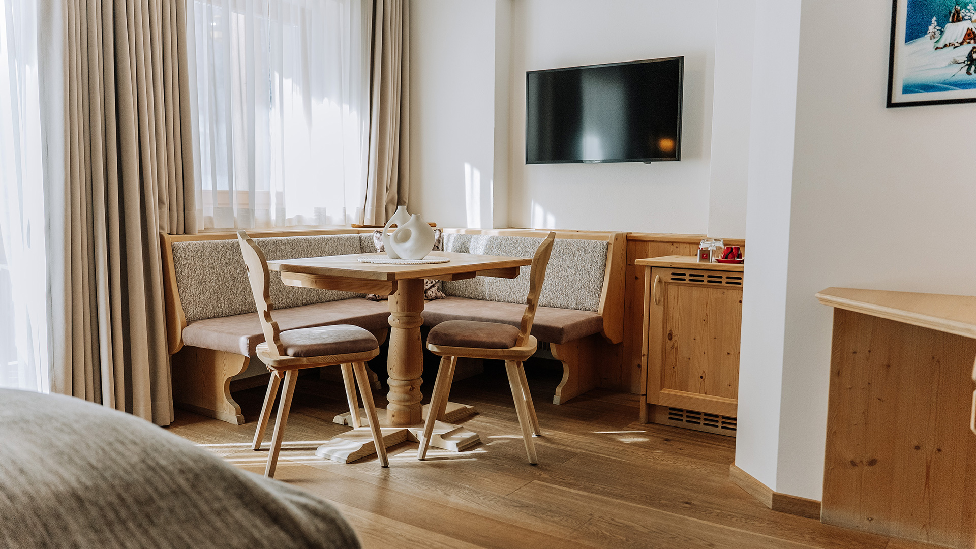 Gemütliche Wohnecke mit Holztisch, Eckbank, Stühlen und Wandfernseher