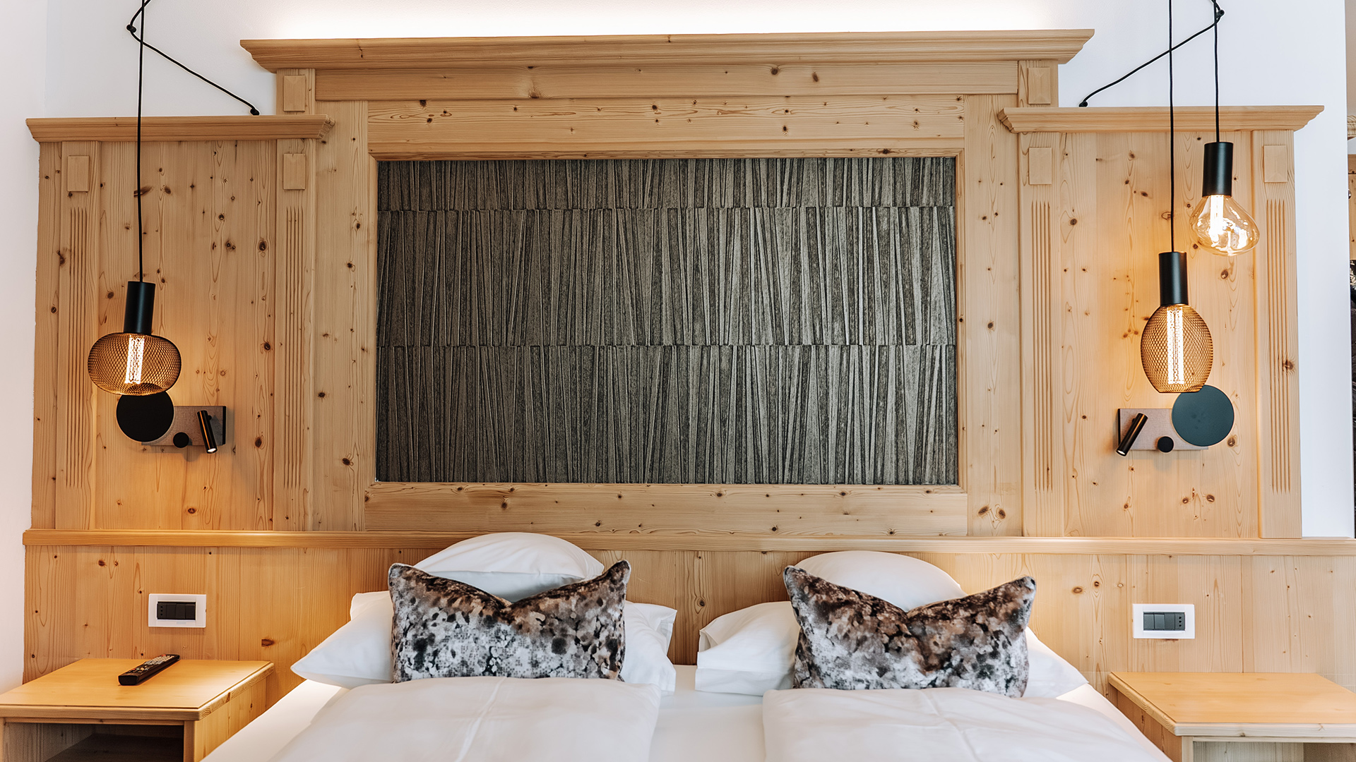 Detail des Comfort Plus Zimmers mit Doppelbett, Holzmöbeln und Designbeleuchtung