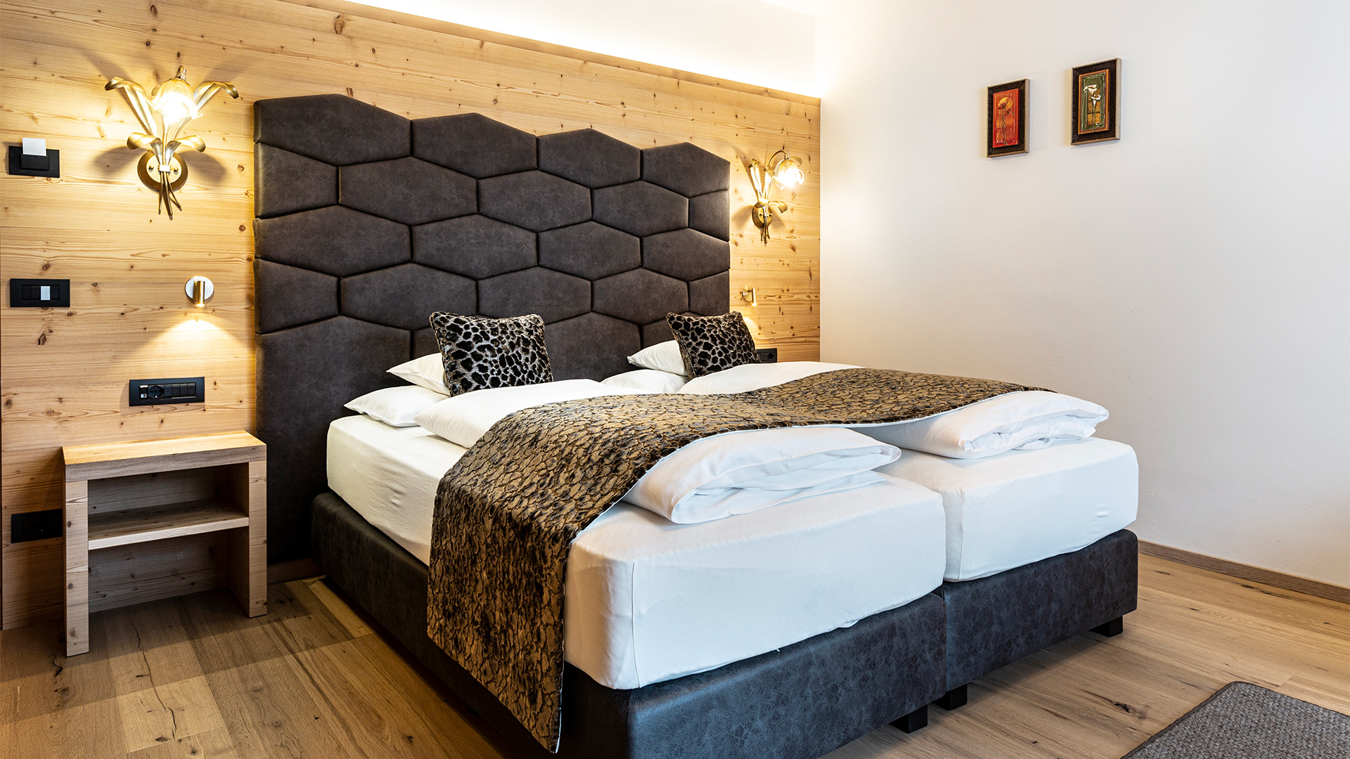 Junior Suite mit zusammengeschobenen Einzelbetten, gepolstertem Kopfteil und Holzverkleidung.