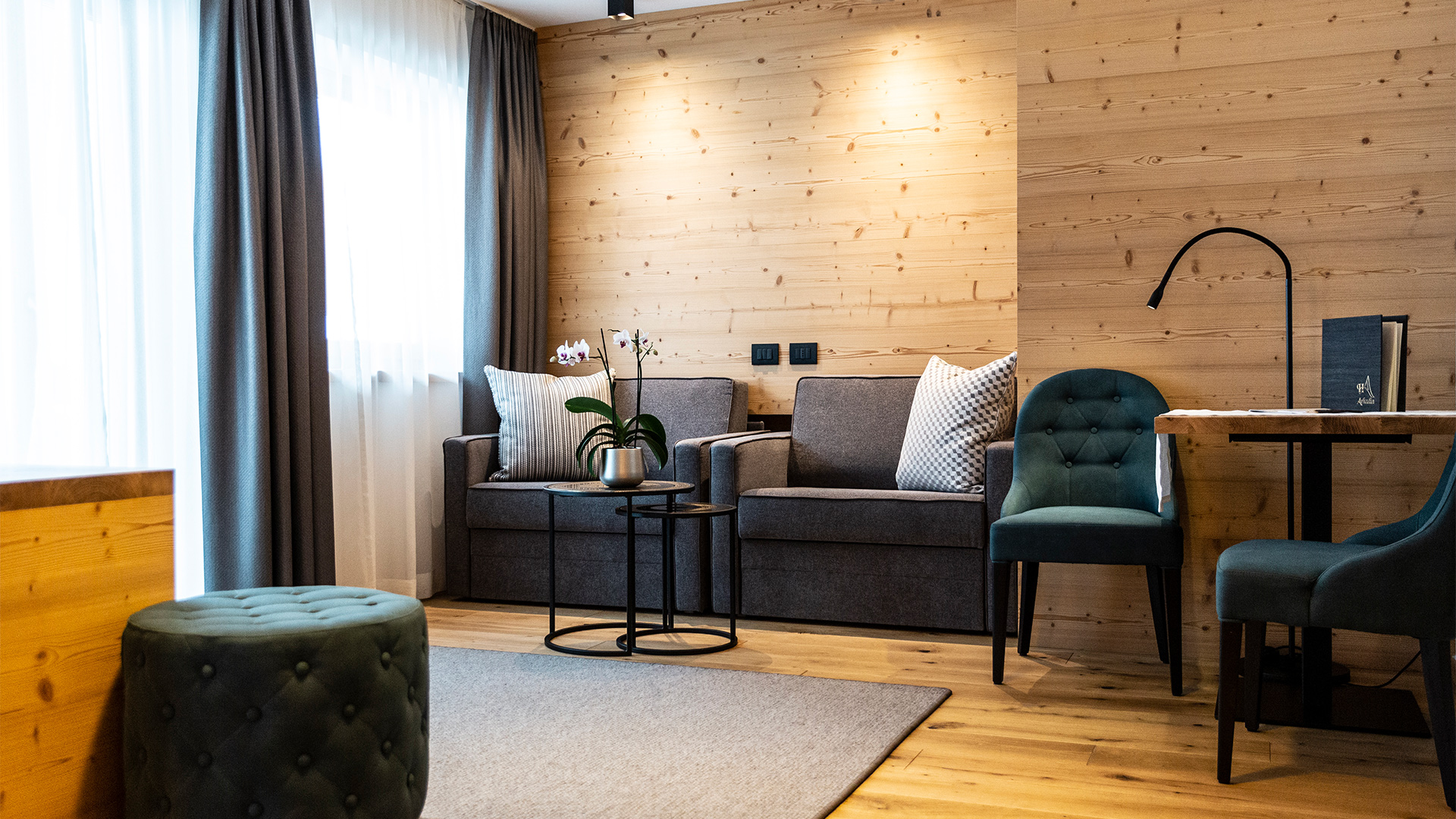 Gemütlicher Entspannungsbereich einer Junior Suite mit kleinen Sofas, Sesseln, einem Couchtisch und Holzmöbeln