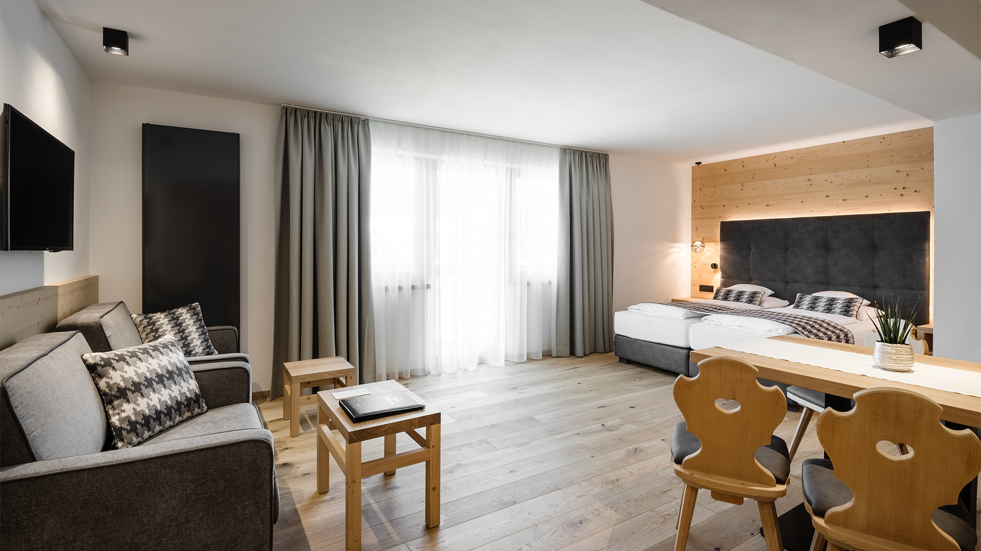 Helles Wohnzimmer einer Junior Suite im Hotel Arkadia mit Holzboden, Ledersofa und Sesseln