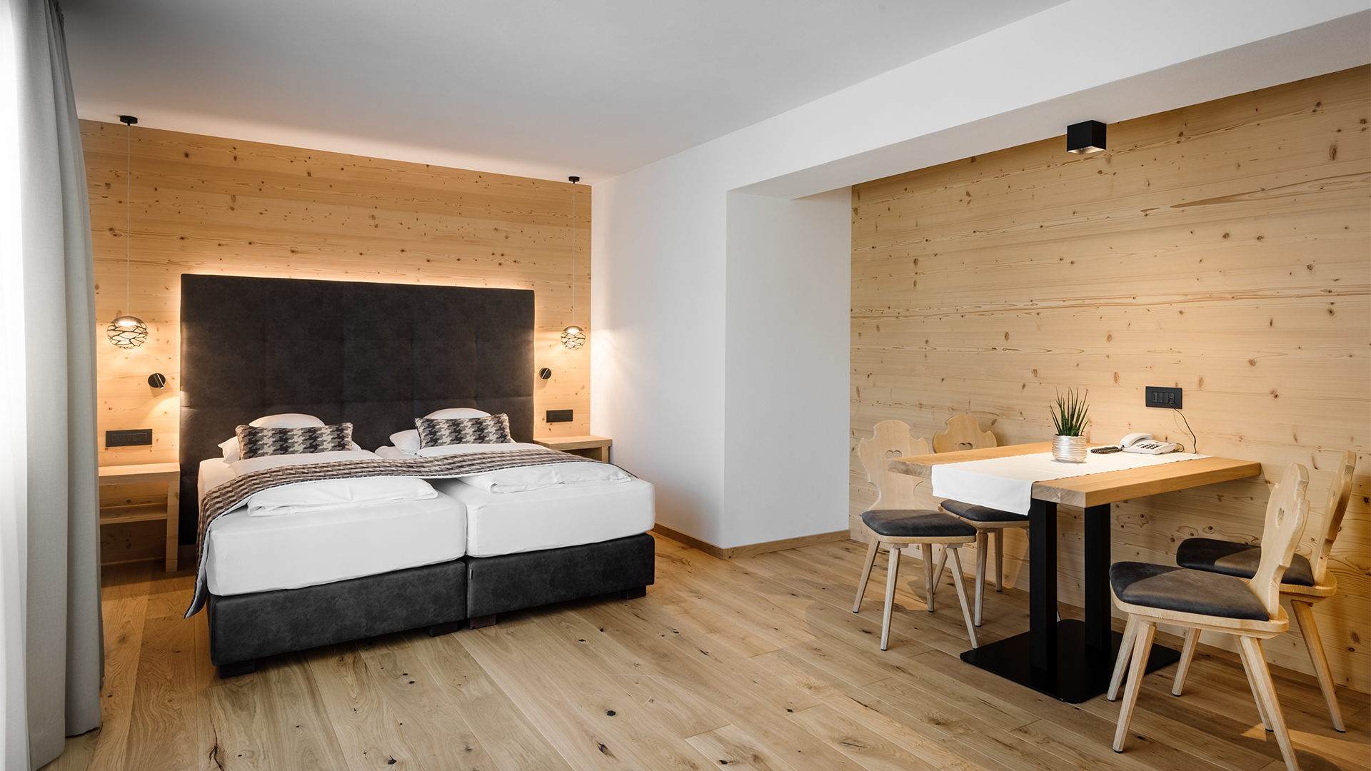 Junior Suite mit Doppelbett, Sitzbereich mit Tisch und Stühlen sowie Holzverkleidung